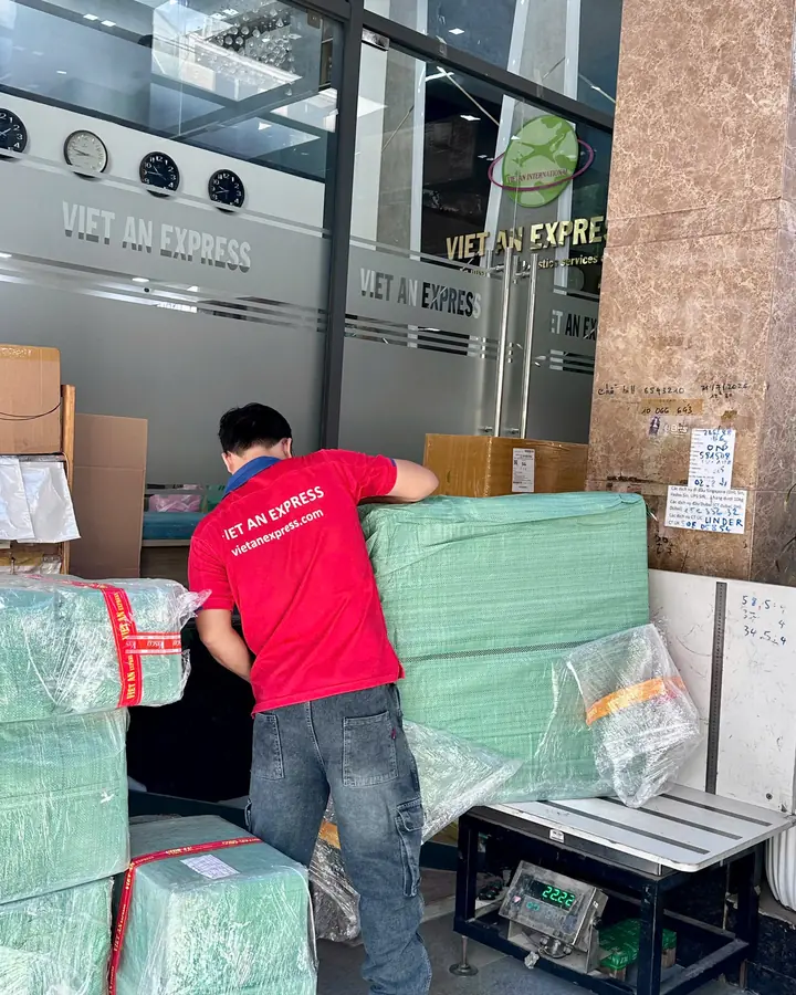 Nhân viên Việt An Express cân kiện hàng bọc xanh trên cân điện tử để tính cước