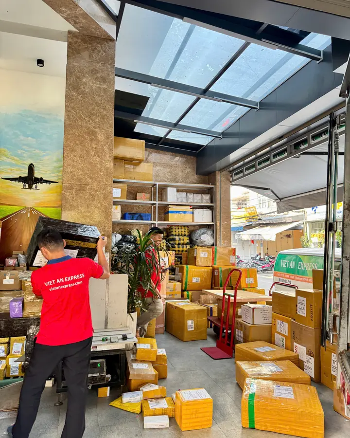 Khu nhận hàng tại trụ sở Việt An Express TP.HCM với kiện hàng xếp trên kệ và nhân viên làm việc